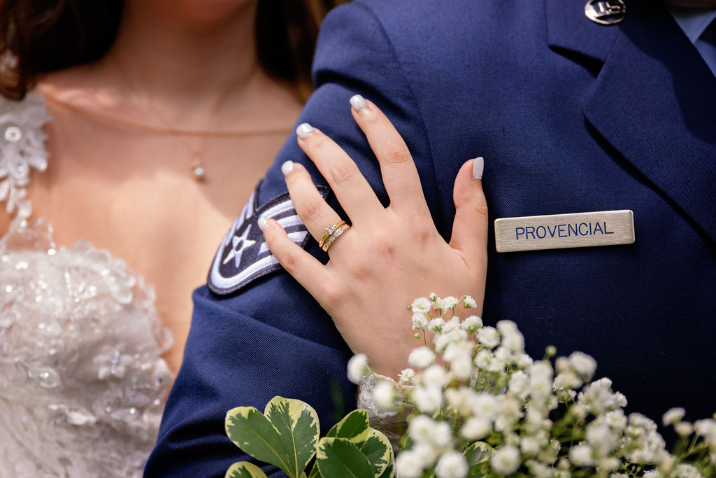 bride's hands on the arm of her groom with her new rings showing